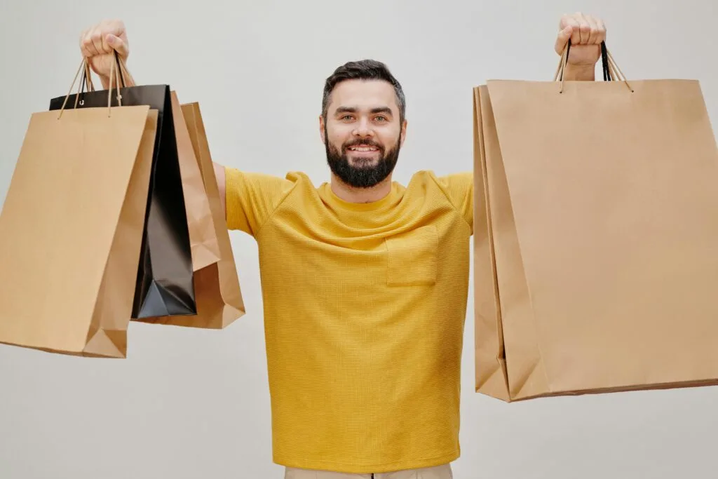 A man happily showing his shopping bags by lifting them up on both hands