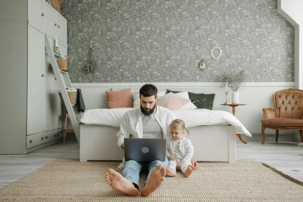 A dad working on his laptop with his baby by his side