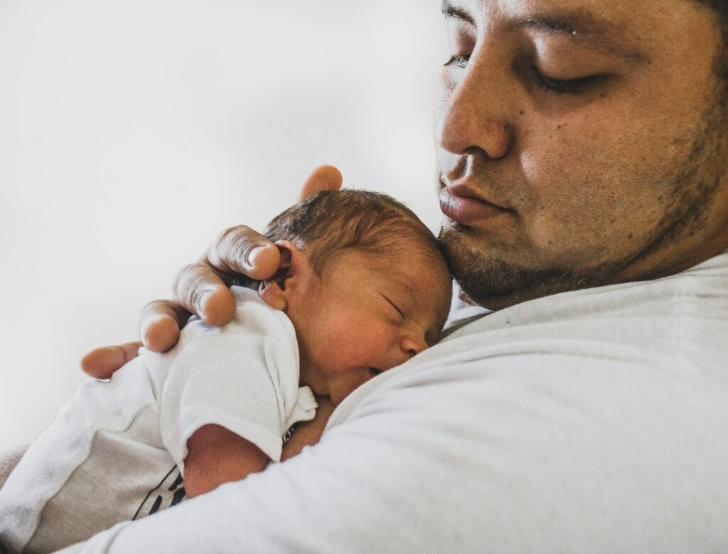 A new dad cuddling a newborn baby